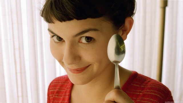 Portrait of Amélie Poulain, a young woman with short dark hair and a curious expression, wearing a red sweater. She is the main character from the 2001 French film “Amélie.”