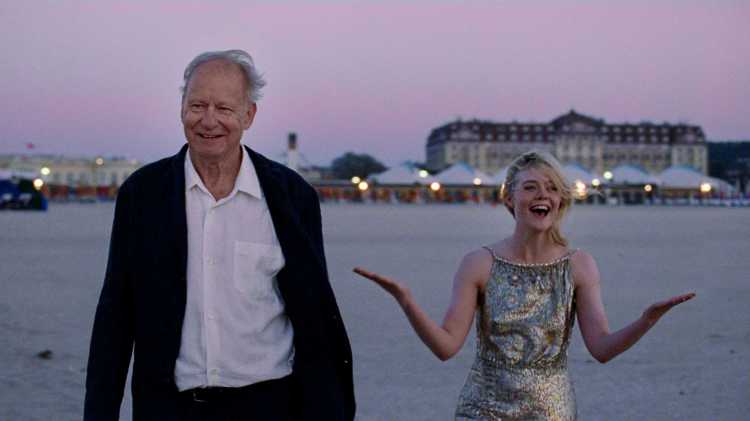 Stellen Skarsgard and Ella Fanning in smart dress in Sentimental Value. Skarsgard is laughing while Fanning holds her arms up looking playfully exacerbated.